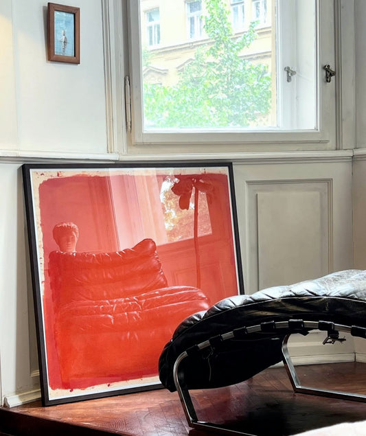Framed artwork of a red sofa in a room with a window