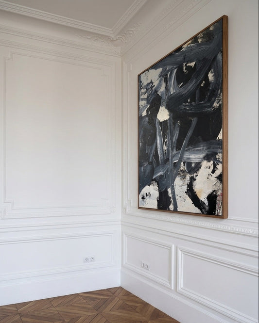 Abstract painting on a wall in a room with white paneled walls and wooden flooring.