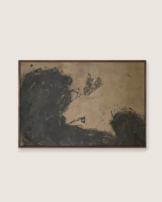 A framed abstract painting featuring dark charcoal and black brushstrokes on a textured beige background, enclosed in a dark brown wooden frame and displayed against a light beige wall.