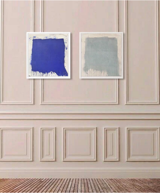 Two abstract paintings on a wall, one in ultramarine blue and the other in seafoam green, with a white frame around each canvas.