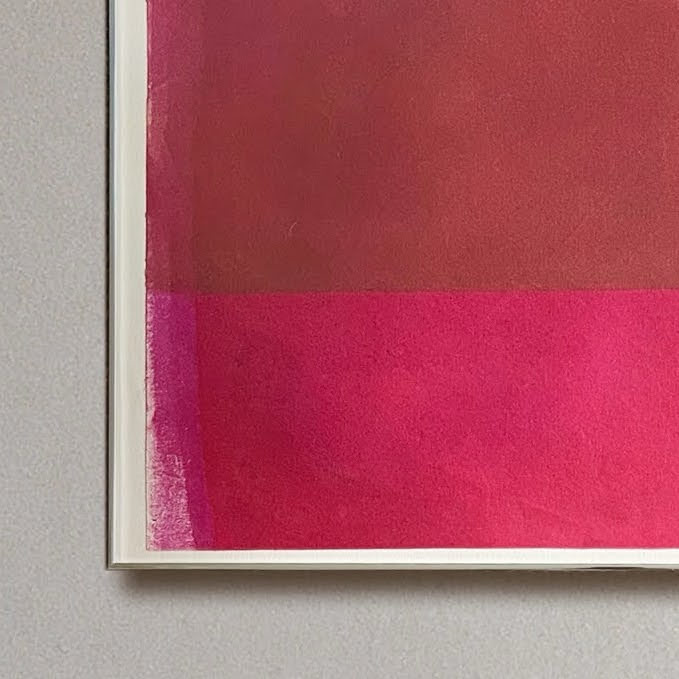 Framed artwork with a pink abstract design on a gray wall