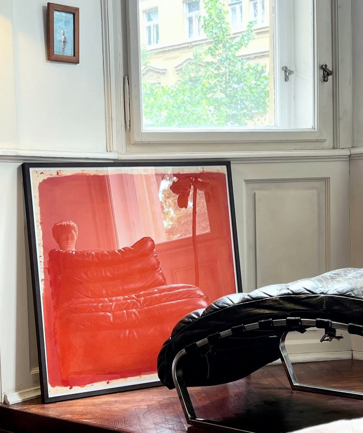 Framed artwork of a red sofa in a room with a window