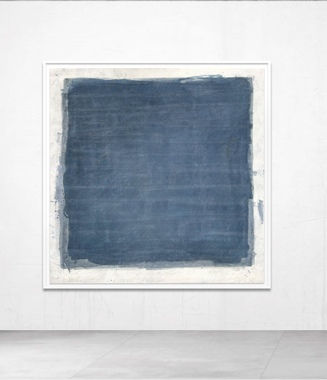 A framed abstract artwork in blue tones, displayed on a wall.