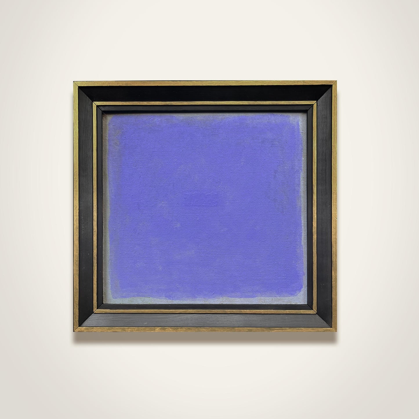 Framed abstract painting with a blue background on a white wall