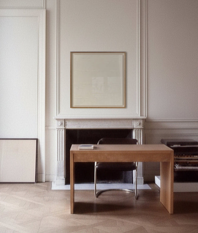 Wooden desk in a room with white paneled walls and a fireplace.