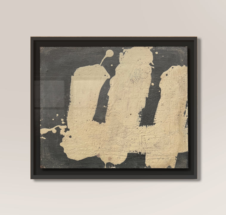 Framed abstract art piece by makelberge with black and gold colors on a beige wall.