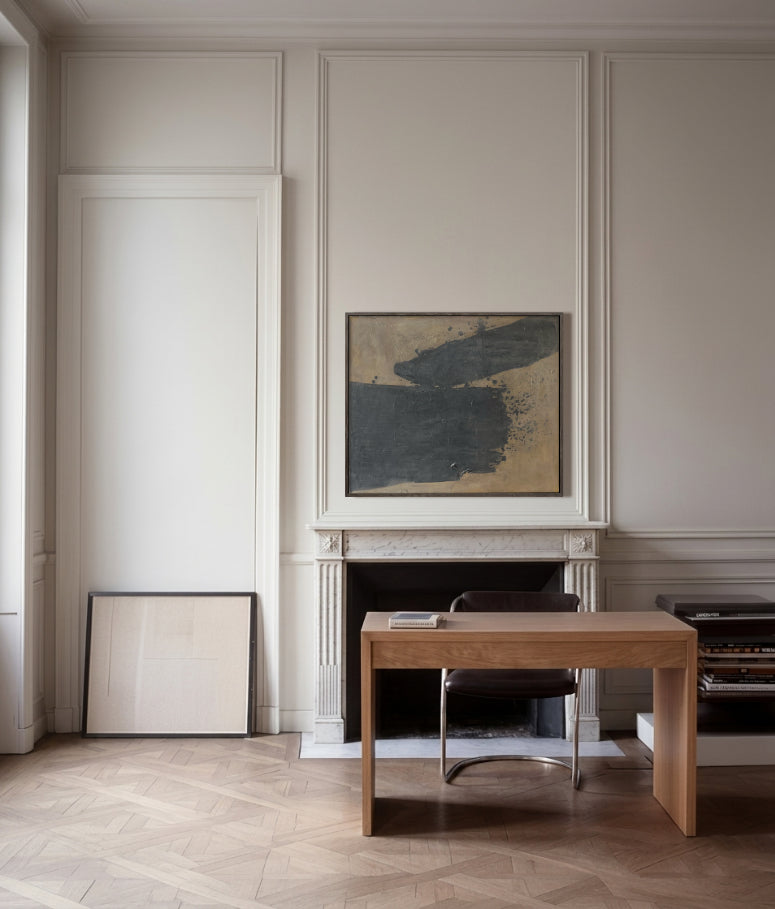 Modern interior with a wooden desk, chair, and abstract painting on a wall.