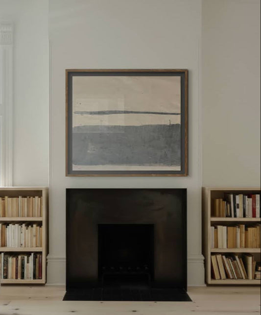 Framed abstract painting above a fireplace with bookshelves on either side.