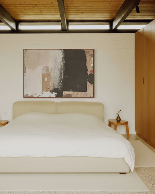 Modern bedroom with a bed, abstract painting, and wooden wardrobe.