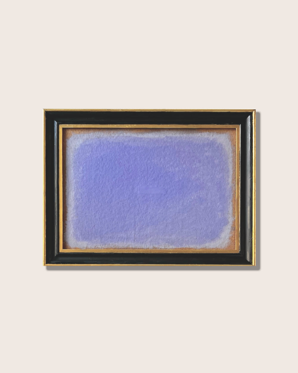 Framed abstract artwork with a blue and gray gradient on a beige wall