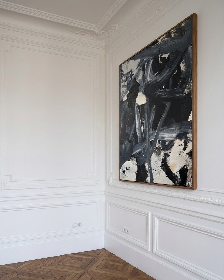 Abstract painting on a wall in a room with white paneled walls and wooden flooring.