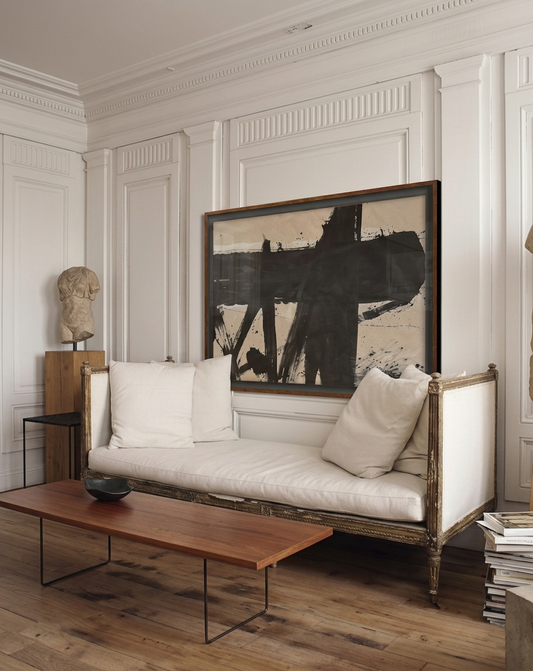 Living room with a white sofa, wooden coffee table, and abstract painting on the wall.