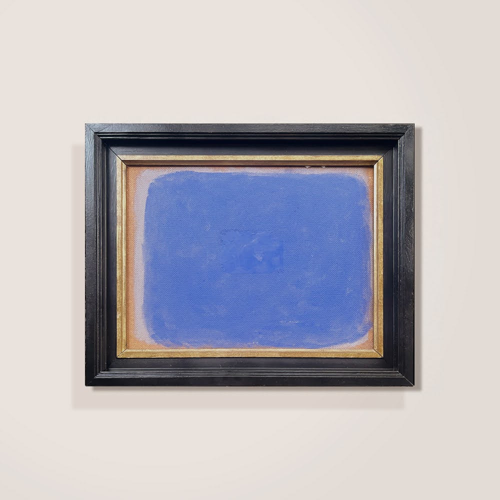Framed abstract painting with a blue center on a beige wall